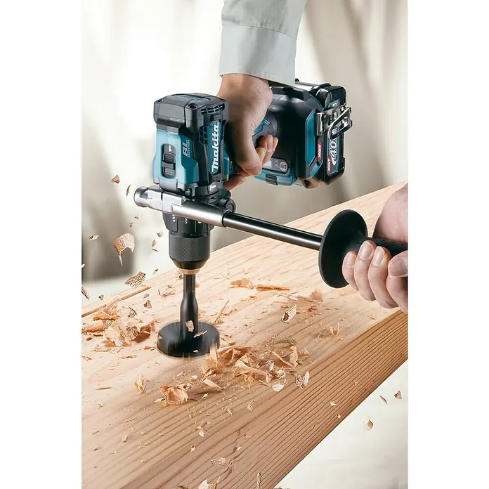 Makita XGT 40V max. Akku-Schlagbohrschrauber HP001GD201 - 40 V, 2 Akkus, 2,5 Ah, 41 Nm - Makita Akku-Bohrmaschine mit großem Holzbohrer bohrt in ein Holzbrett und erzeugt Späne. Eine Person bedient Bohrmaschine und Zusatzgriff.