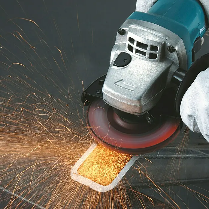 Makita Elektro-Winkelschleifer 9558HNRZ - 840 W, Leerlaufdrehzahl: 11.000 U/min - Ein Winkelschleifer in Türkis und Silber schleift Metall und erzeugt einen Funkenregen.