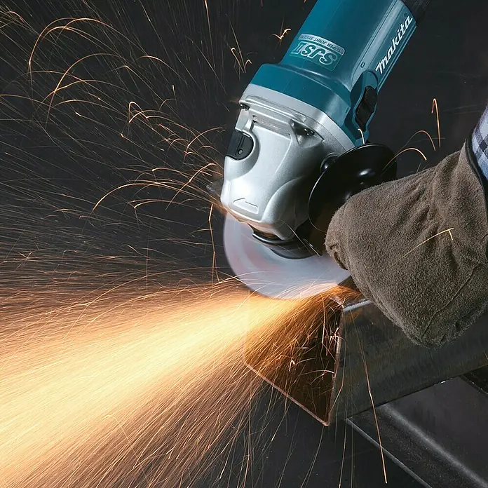 Makita Elektro-Winkelschleifer GA5040CZ1 - 1.400 W, Leerlaufdrehzahl: 11.000 U/min - Blau-silberner Makita Winkelschleifer schneidet Metall, von behandschuhter Hand gehalten, erzeugt helle Funken.