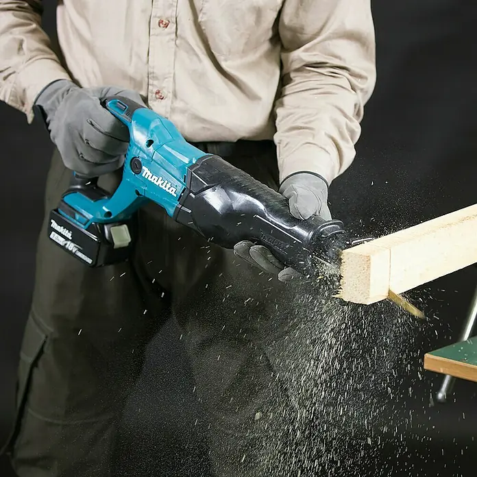 Makita LXT 18V Akku-Säbelsäge DJR186RT - 18 V, 1 Akku, 5 Ah, Leerlaufhubzahl: 0 /min - 2.800 /min - Person schneidet Holzbalken mit einer türkisfarbenen und schwarzen Akku-Säbelsäge, Späne erzeugend.