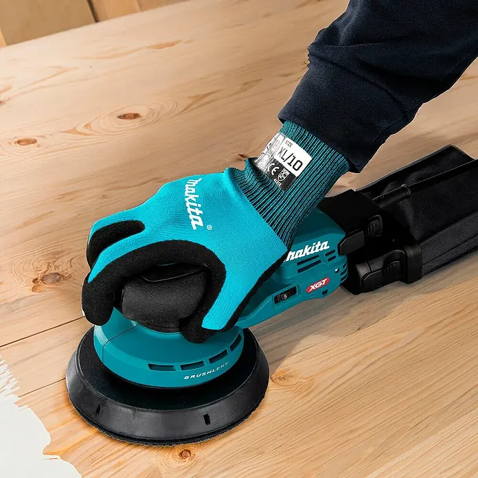 Makita XGT 40V max. Akku-Exzenterschleifer BO004CGZ - 40 V, Ohne Akku, Durchmesser Schleifteller: 150 mm - Person benutzt einen tealfarbenen und schwarzen Makita Exzenterschleifer auf Holz, trägt einen Makita Handschuh.