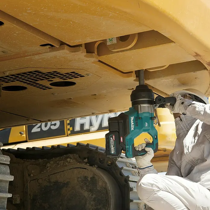 Makita XGT 40V max. Akku-Schlagschrauber TW010GZ - 40 V, Ohne Akku, 3.150 Nm - Arbeiter nutzt einen türkis-schwarzen Makita 40V Schlagschrauber an einem gelben Bagger.