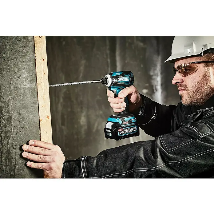 Makita XGT 40V max. Akku-Schlagschrauber TD001GD201 - 40 V, 2 Akkus, 2,5 Ah - Mann verwendet einen blau-schwarzen Makita Schlagschrauber mit langem Bit, um eine Schraube in Holz zu treiben. Er trägt Schutzhelm und -brille.