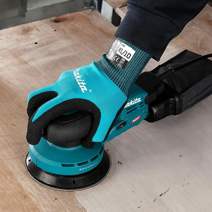 Makita XGT 40V max. Akku-Exzenterschleifer - 40 V, Ohne Akku, Durchmesser Schleifteller: 125 mm - Eine behandschuhte Hand bedient einen türkisen Makita Exzenterschleifer auf einer hellen Holzoberfläche.