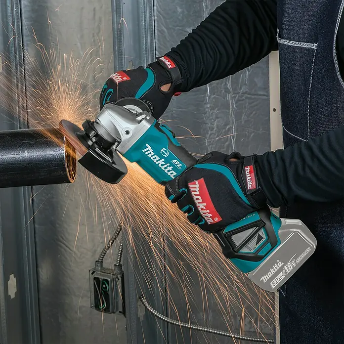 Makita LXT 18V Akku-Winkelschleifer DGA513Z - 18 V, Ohne Akku, Durchmesser Scheibe: 125 mm - Eine Person mit Handschuhen verwendet einen türkisfarbenen und schwarzen Makita Akku-Winkelschleifer, um ein Metallrohr zu schneiden, wobei Funken entstehen.