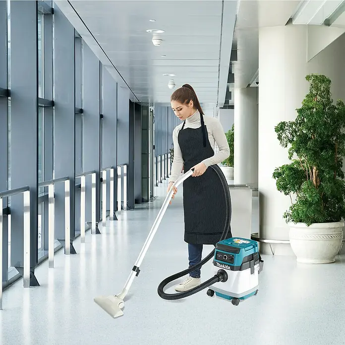 Makita LXT 18V Akku-Nass-Trockensauger DVC150LZ - 36 V, Ohne Akku, Behältervolumen: 15 l - Eine Frau saugt einen großen modernen Flur mit einem türkis-weißen Makita Nass-Trockensauger.