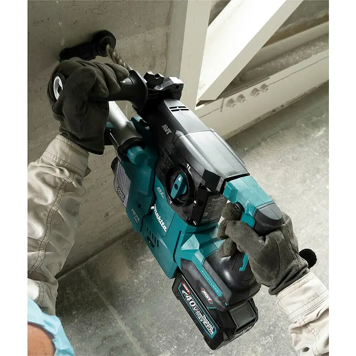 Makita XGT 40V max. Akku-Kombihammer HR008GZ - 40 V, Ohne Akku, 3,9 J - Eine Person mit Handschuhen bohrt mit einem türkis-schwarzen Makita 40V Bohrhammer mit Staubabsaugung in Beton.