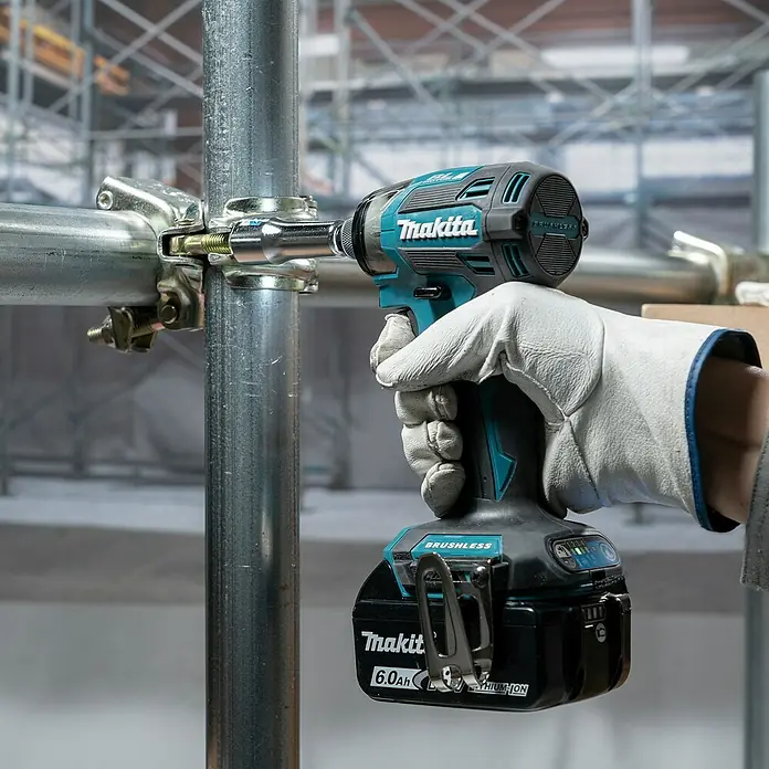 Makita LXT 18V Akku-Schlagschrauber DTD173Z - 18 V, Ohne Akku - Eine behandschuhte Hand verwendet einen türkis-schwarzen Makita Schlagschrauber mit 6,0Ah Akku, um eine Klemme an einem Gerüstrohr zu befestigen.