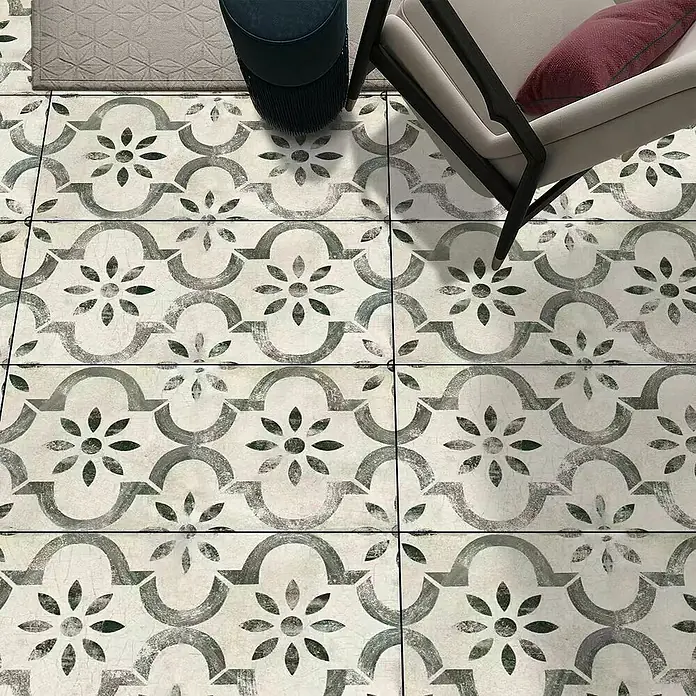 Suelo vinílico SCP Hidráulico Gaudí - 1.200 x 600 x 5 mm, Gris, Resistente al agua - Azulejos de suelo con un patrón floral y geométrico gris verdoso desgastado, vistos en un ambiente de sala con muebles.