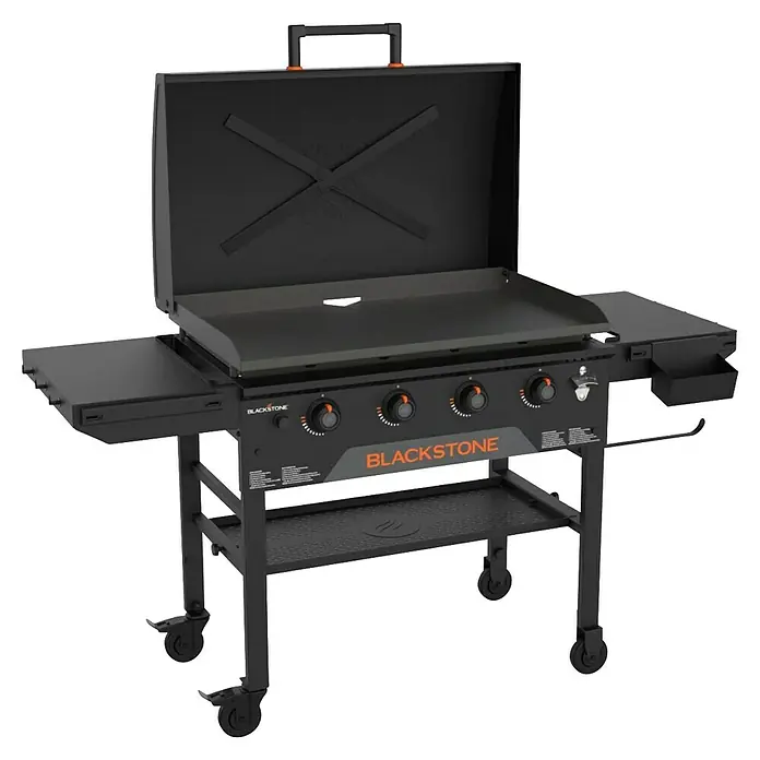 Blackstone Plancha Grill - Superficie de la parrilla (An x Pr): 91 x 55 cm, Negro, Número de quemadores: 4 ud. - Plancha Blackstone negra con tapa abierta, detalles naranjas y ruedas, con varios quemadores y estantes laterales.