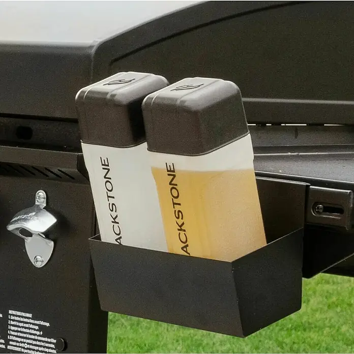 Blackstone Plancha Grill - Superficie de la parrilla (An x Pr): 91 x 55 cm, Negro, Número de quemadores: 4 ud. - Soporte metálico negro con dos botellas exprimibles Blackstone (líquido blanco y ámbar) montado en una parrilla.