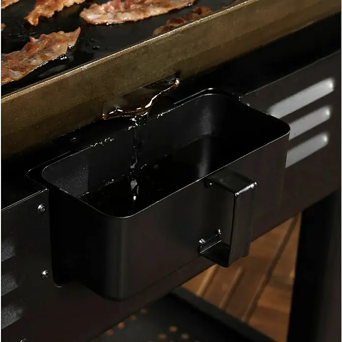 Blackstone Plancha Grill - Superficie de la parrilla (An x Pr): 91 x 55 cm, Negro, Número de quemadores: 4 ud. - Bandeja de goteo de grasa de metal negro recogiendo la grasa de una plancha con tocino.