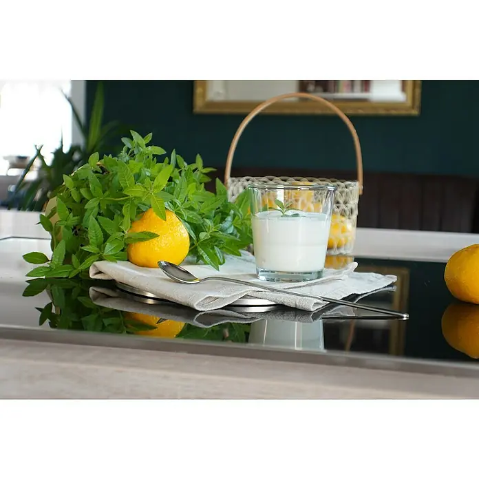 Blu Bio Orangenverbene - Lippia citriodora, Topfgröße: 12 cm - Glas Joghurt mit Minzzweig, frischen grünen Blättern und leuchtend gelben Zitronen auf einer Leinenserviette mit Löffel auf glänzender Oberfläche.