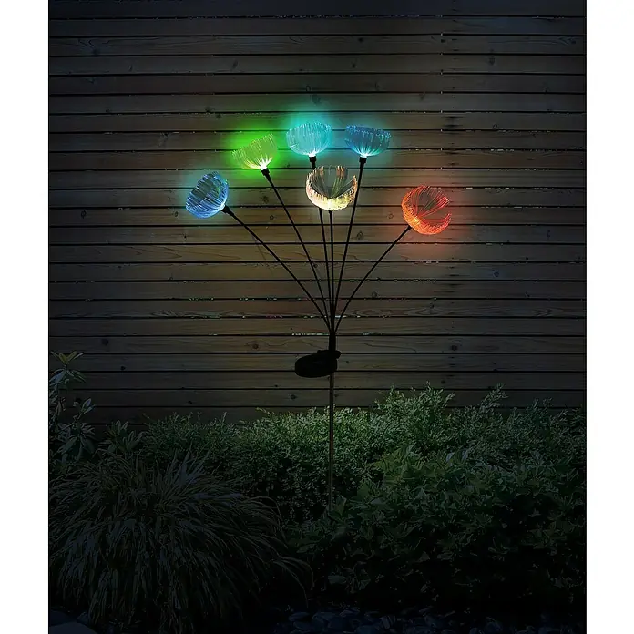 Globo Solar-Dekoleuchte - LED, IP44, Höhe: 70 cm - Solar-Gartenleuchte mit mehreren bunten faseroptischen Blütenlichtern, die ein Gartenbeet vor einem Zaun bei Nacht beleuchten.
