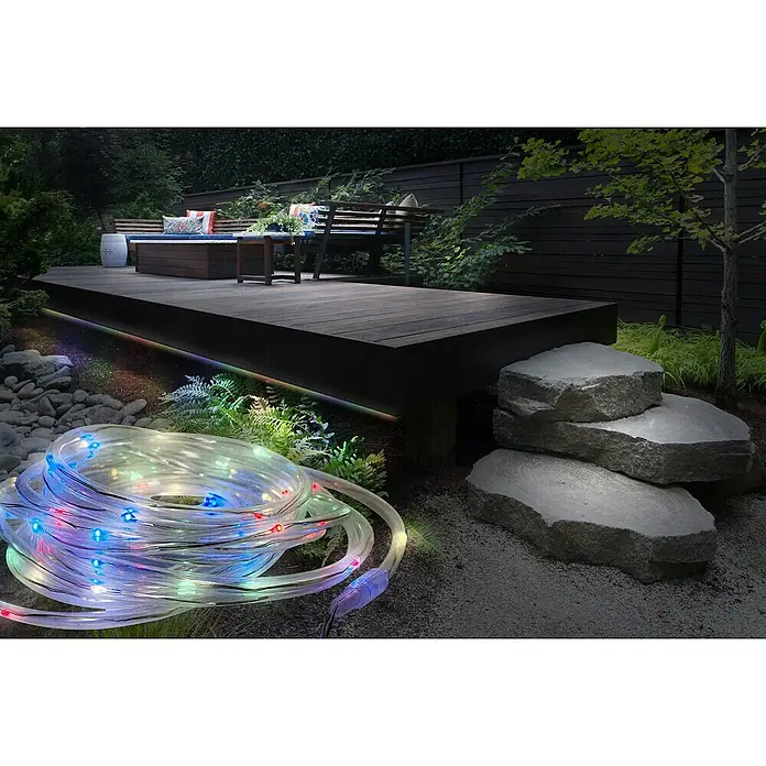 Globo LED-Solar-Lichterkette - Außen, 4,9 m, RGB - Aufgerollte transparente Lichterkette mit mehrfarbigen LEDs im Garten neben einer beleuchteten Terrasse.