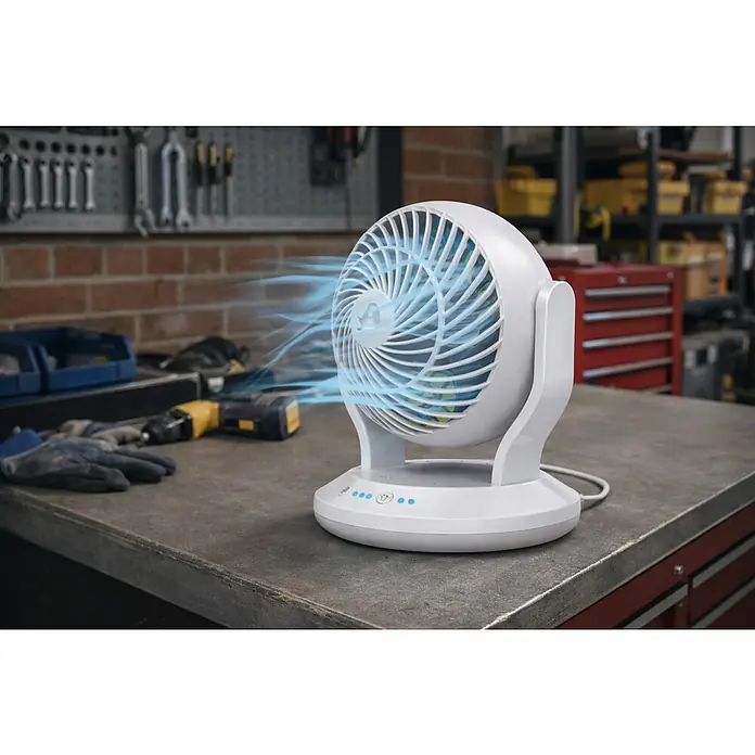 Arctic Air Tischventilator Gyro Cool - Weiß - Weißer Tischventilator mit sichtbarem blauem Luftstrom, der auf einer Werkbank in einer Werkstatt arbeitet.