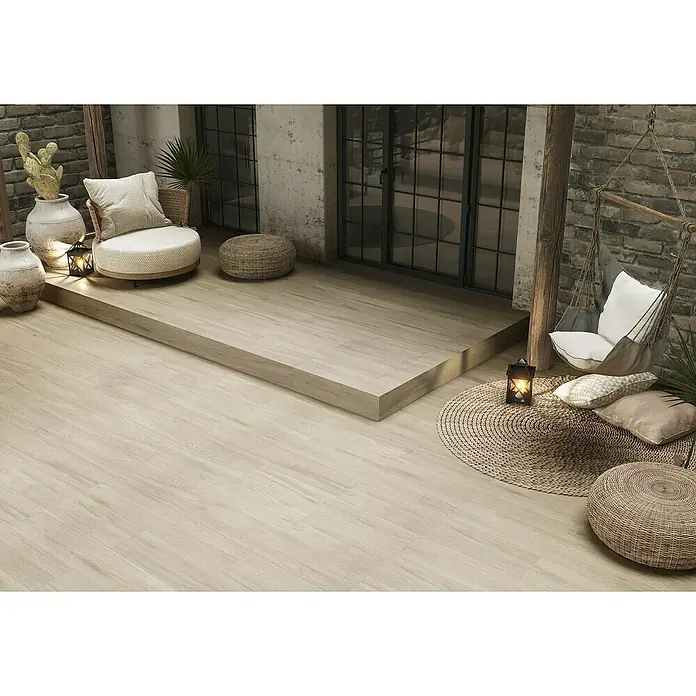 Pavimento cerámico Nook - 57 x 19 cm, Gris, Mate - Tarimas efecto madera clara que crean un cálido patio exterior con plataforma elevada y áreas de asiento.