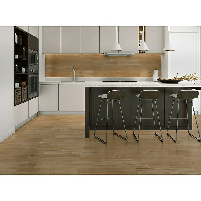 Pavimento porcelánico Hardy - 15,3 x 58,9 cm, Miel, Mate - Cocina moderna con isla oscura, tres taburetes, salpicadero de madera clara y suelo de madera.
