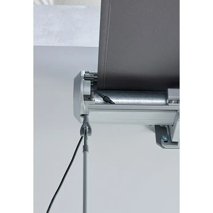 Sunfun LED-Vollkassettenmarkise - Anthrazit, Breite: 3 m, Ausfall: 2 m - Nahaufnahme eines grauen Rolladenmechanismus mit silbernem Metallgehäuse, teilweise ausgerolltem Stoff und angeschlossenem Stromkabel.