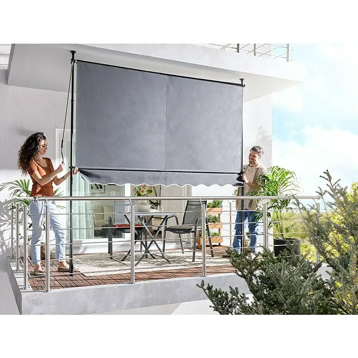 Sunfun Klemmmarkise / Senkrechtmarkise - Anthrazit, Breite: 3 m, Ausfall: 1,3 m - Grauer Balkon-Sichtschutz wird von einem Paar auf einem modernen Balkon installiert.