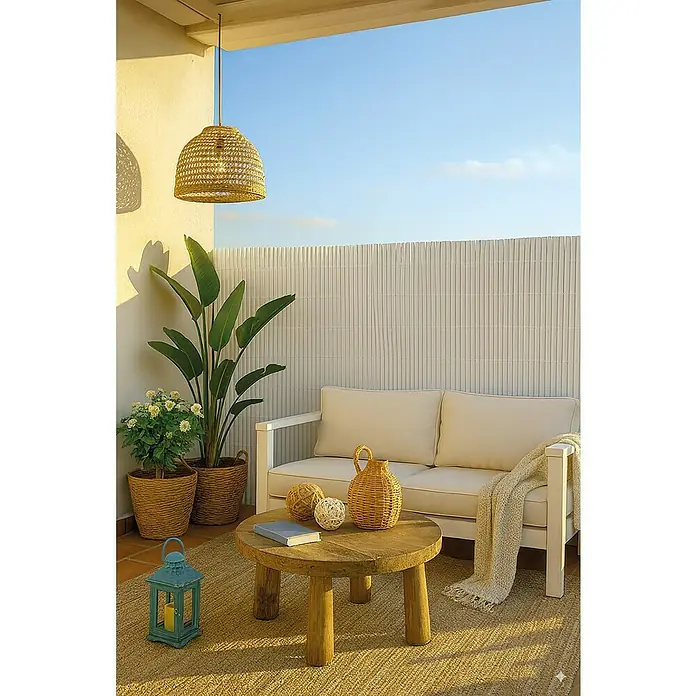 Ocultación Cañizo de PVC ovalado - Blanco, 3 x 1 m, PVC - Acogedora terraza exterior con sofá blanco, mesa redonda de madera y alfombra de yute, rodeada de plantas, bajo una lámpara colgante trenzada.