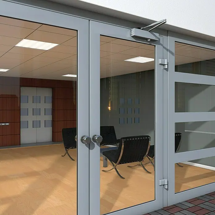 Basi Türschließer TS 200 - L x B x H: 210 x 40 x 50 mm, Silber - Grau gerahmte Glastüren mit einem oberen Türschließer, führen in ein modernes Büro.