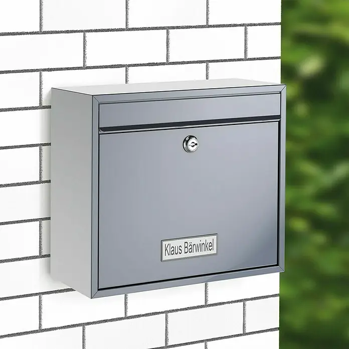 Basi Wandbriefkasten BK 900 - L x B x H: 11,6 x 36 x 31,5 cm, Edelstahl, Edelstahl, Namensschild - Silbergrauer Metallbriefkasten mit Schloss und Namensschild 'Klaus Bärwinkel', an einer Wand montiert.