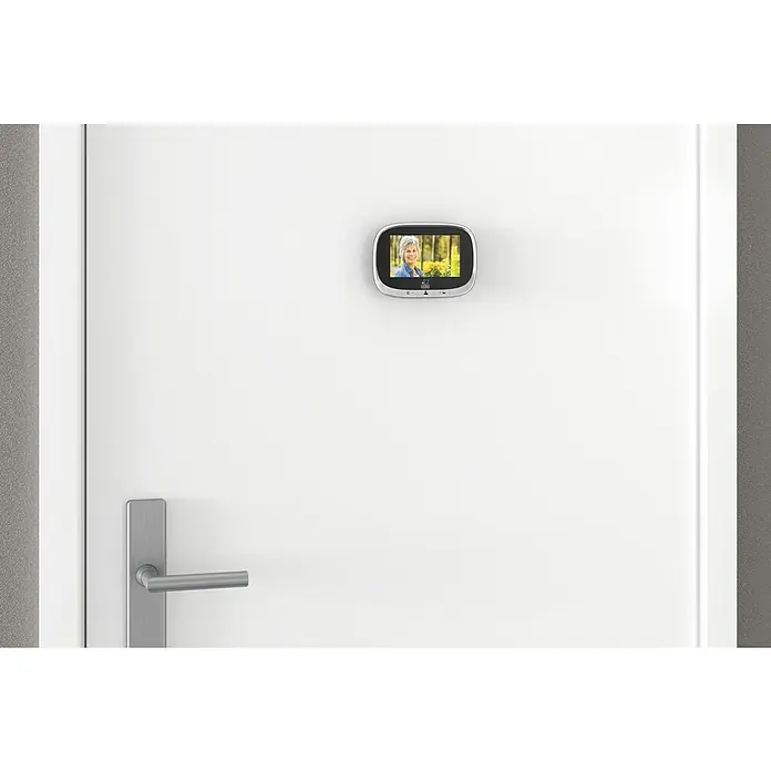Basi Digitaler Türspion TS 810 - Einbaumaß: Ø 14 - 22 mm, TFT-Bildschirm, Stärke Tür: 35 mm - 120 mm - Digitaler Türspion in Silber auf weißer Tür, zeigt Frau mit Blumen. Darunter ein silberner Türgriff.