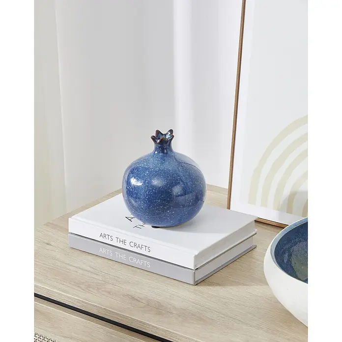 Eglo Dekofigur Shigay - Ø x H: 19 x 20 cm, Blau - Blau gesprenkelter Keramik-Granatapfel als Dekorationsobjekt, auf Büchern auf einer Holzoberfläche.