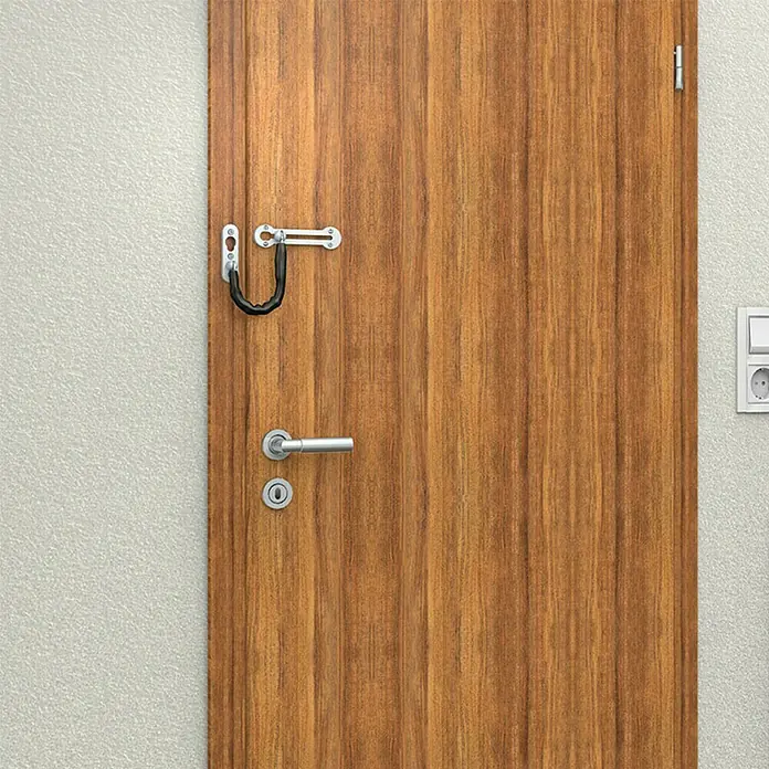 Basi Türkette TK 21 - Kettenlänge: 18,5 cm, Silber - Silberne Metall-Türsicherungskette mit schwarzem Schutz an einer hellbraunen Holztür mit Griff und Schloss.