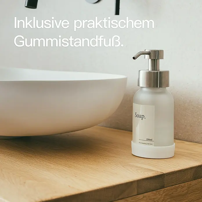 Designfabrik Hamburg Seifenspender - Edelstahl, Silber/Satiniertes Glas - Seifenspender aus Milchglas mit Edelstahlpumpe und praktischem Gummistandfuß, neben einem Waschbecken.