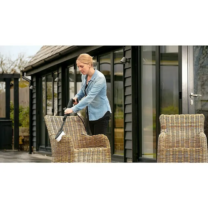 Bosch Hochdruckreiniger EasyAquatak 110 - 1.300 W, Max. Druck: 110 bar, Fördermenge: 330 l/h - Hochdruckreiniger-Bürstenaufsatz reinigt einen hellbraunen Korbsessel auf einer Terrasse.