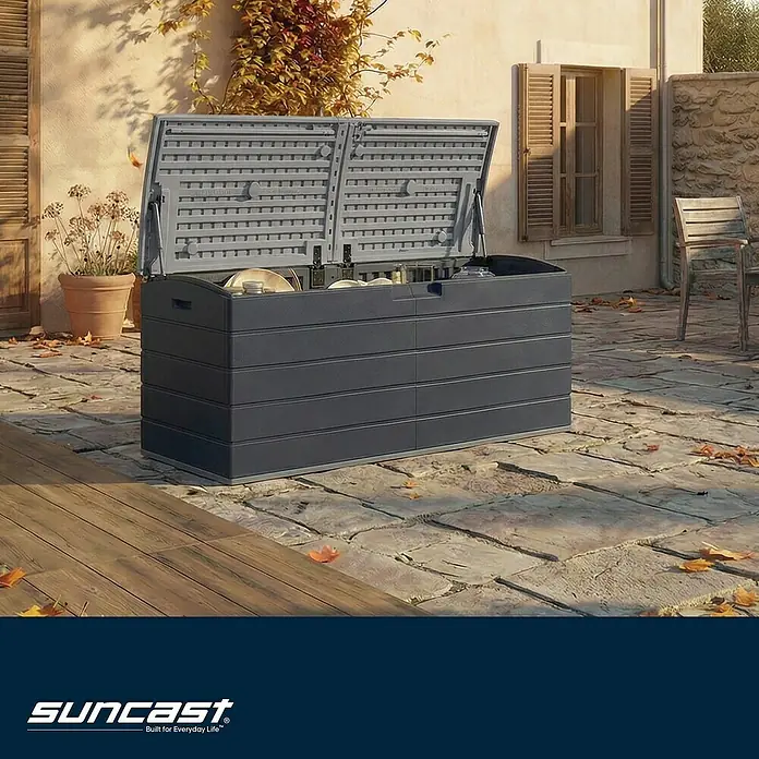 Suncast Kissenbox Harbour Bay - L x B x H: 150 x 61 x 64 cm, Kunststoff, Anthrazit - Dunkelgraue Kunststoff-Gartenbox mit geöffnetem Deckel auf einer Steinterrasse, zeigt Geschirr und Flaschen.