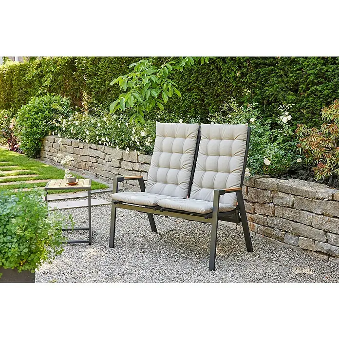 Siena Garden Atria Sitzauflage - L x B x H: 123 x 48 x 6 cm, Silber, Polyester, 1 Stk. - Zweisitzer-Gartenbank mit dunkelgrauem Gestell, Holzarmlehnen und beigen Kissen, neben passendem Beistelltisch im Garten.