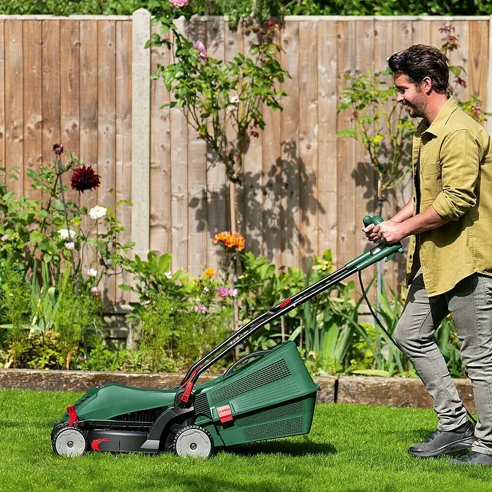 Bosch Elektro-Rasenmäher UniversalRotak 37-550 - 1.400 W, Schnittbreite: 370 mm - Ein Mann mäht mit einem grünen Bosch Rasenmäher auf einer sonnigen Wiese.