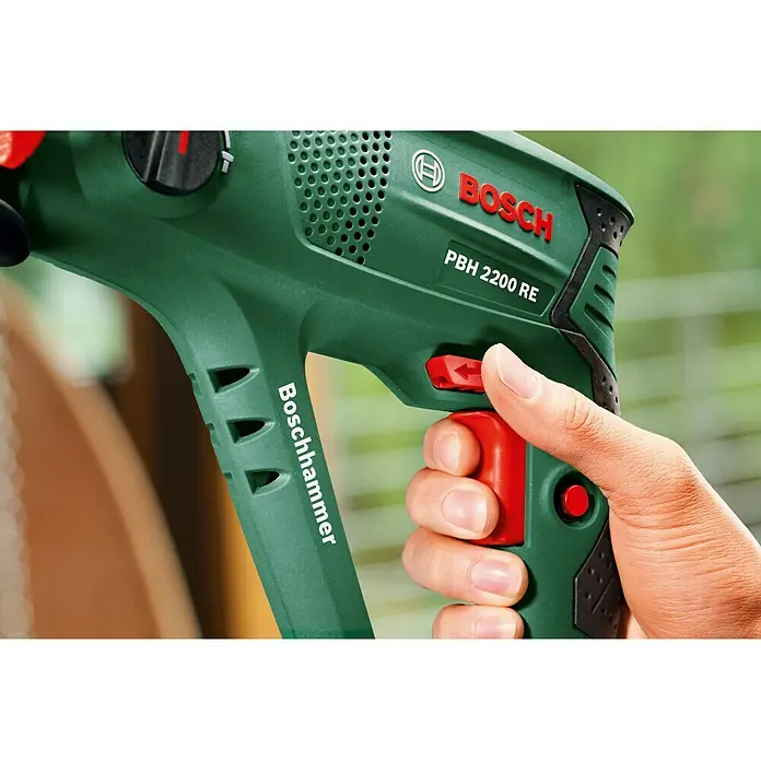 Bosch Kombihammer PBH 2200 RE - 570 W, 1,8 J, SDS-Plus-Aufnahme - Nahaufnahme eines Bosch PBH 2200 RE Bohrhammers in Aktion, gehalten von einer Hand. Das Werkzeug ist grün mit roten Akzenten.