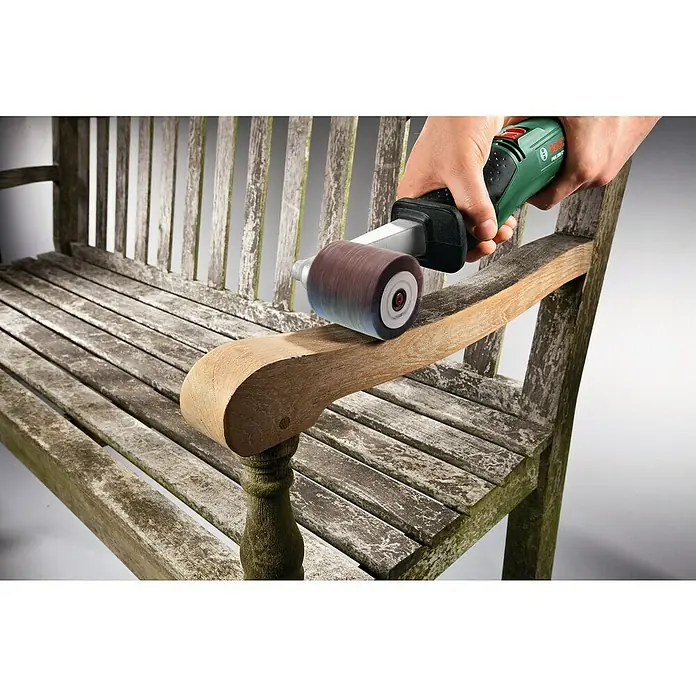 Bosch Lamellenschleifrolle - Breite: 60 mm, Passend für: Bosch Schleifroller PRR 250 ES, Körnung: 120 - Person schleift eine verwitterte Holzbank-Armlehne mit einem grün-schwarzen Bandschleifer, frisches Holz wird sichtbar.