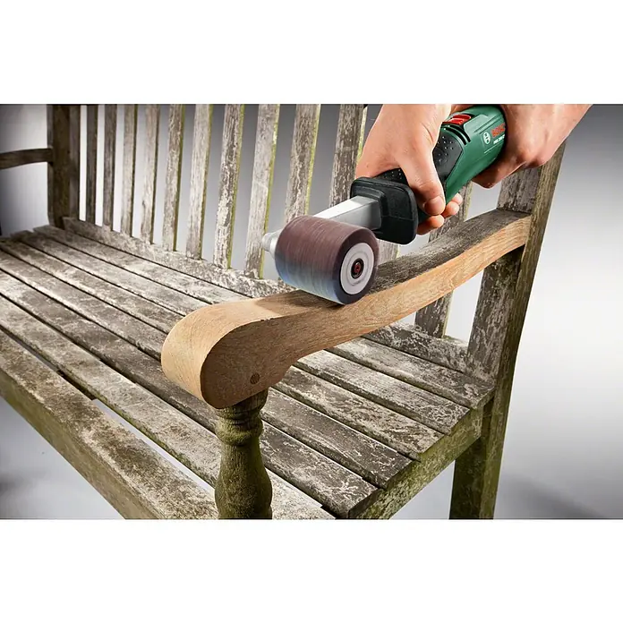 Bosch Lamellenschleifrolle - Breite: 60 mm, Passend für: Bosch Schleifroller PRR 250 ES, Körnung: 120 - Hand hält grünen und schwarzen Schleifer mit rotierender Walze, schleift Armlehne einer alten Holzbank zur Oberflächenerneuerung.