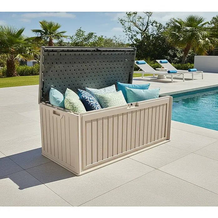 Westmann Kissenbox Alba - 63 x 128 x 64 cm, Kunststoff, Beige - Beige Outdoor-Aufbewahrungsbox mit offenem dunklem Deckel, gefüllt mit blauen und grünen Kissen, am Pool.