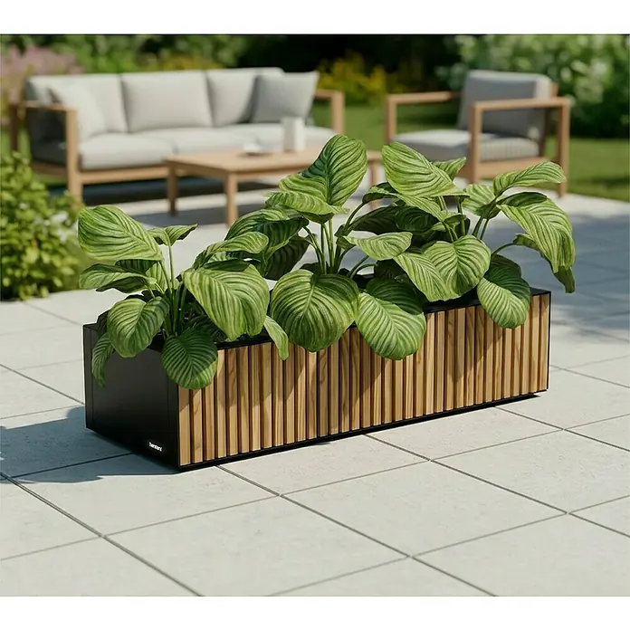 Herstera Garden Pflanzkasten Deco Planter - Außenmaß (L x B x H): 100 x 40 x 25 cm, Holz, Braun/Schwarz - Rechteckiger Pflanzkübel mit schwarzem Rahmen und Holzleisten, mit grüner Pflanze auf einer gefliesten Terrasse. Gartenmöbel im Hintergrund.