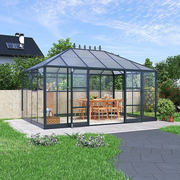 Westmann Gewächshaus Suprema XL - Außenbreite inkl. Dachüberstand: 421 cm, Schwarz - Dunkelgraues Gewächshaus mit transparenten Scheiben, eingerichtet mit Holztisch und Stühlen, in einem grünen Garten.