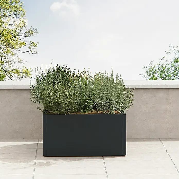 Herstera Garden Pflanzkasten Cube - Außenmaß (L x B x H): 100 x 100 x 50 cm, Metall, Anthrazit - Schwarzes rechteckiges Pflanzgefäß mit grünen Pflanzen auf einer modernen Terrasse.