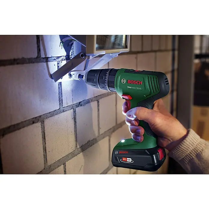 Bosch Power for All 18V Maschinen-Set 2-Tool-Kit EasyImpact + EasySaw - 18 V, 2 Akkus, 2 Ah, 5 -tlg. - Eine Person verwendet einen grün-schwarzen Bosch EasyImpact 18V-40 Bohrschrauber an einer Ziegelwand.