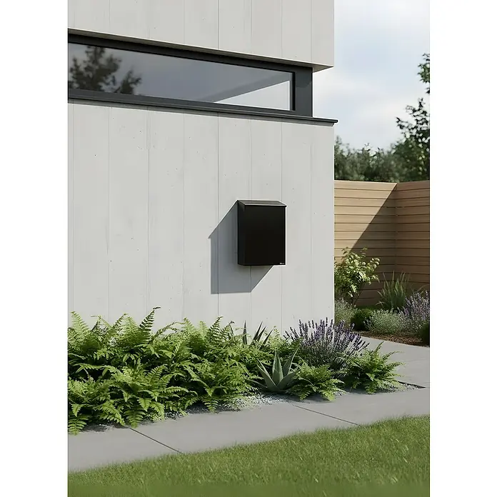 Allux Briefkasten 200 - L x B x H: 140 x 280 x 390 mm, Schwarz, Stahl - Moderner schwarzer Briefkasten an einer weißen Wand, umgeben von Pflanzen.