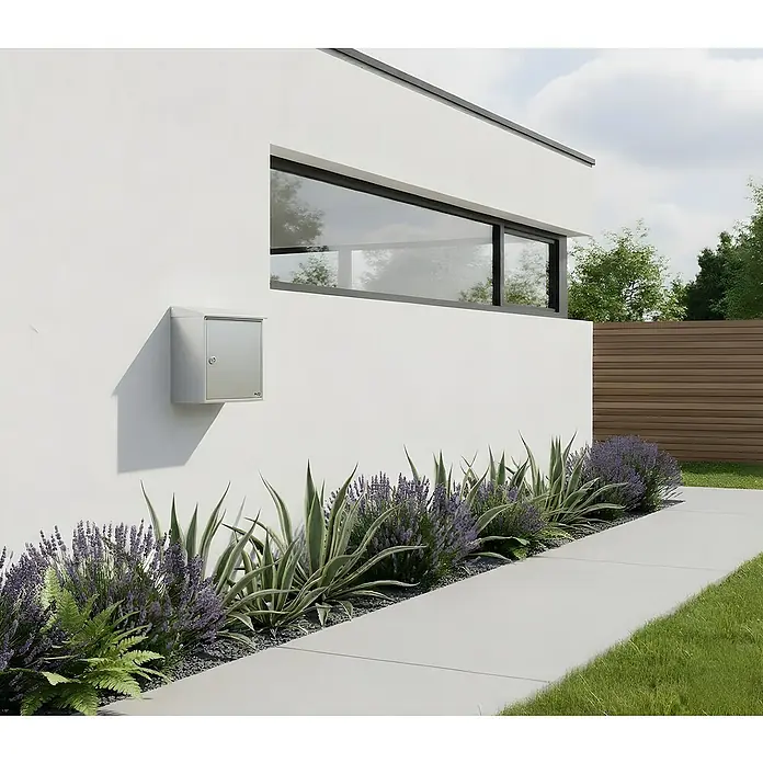 Allux Standbriefkasten LT150 - L x B x H: 150 x 390 x 330 mm, Silber, Stahl - Silberner Briefkasten an moderner weißer Hauswand, umgeben von Lavendel und Laub.