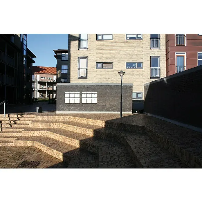 Allux Briefkasten KS200 - L x B x H: 170 x 400 x 445 mm, Weiß, Stahl, Namensschild - Geometrische Außentreppen und Wegpflasterung aus hellbraunen und beigefarbenen Ziegeln, harmonisch in einen modernen Wohnplatz integriert.