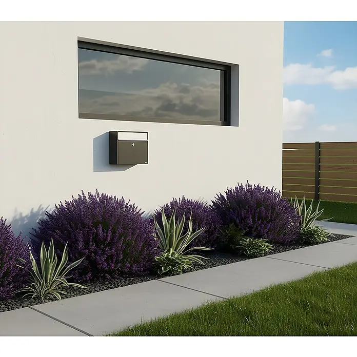 Allux Briefkasten 250 - L x B x H: 150 x 360 x 360 mm, Anthrazit, Stahl - Moderner, dunkelgrauer Briefkasten an weißer Hauswand, umgeben von lila Blumen und Grünpflanzen.