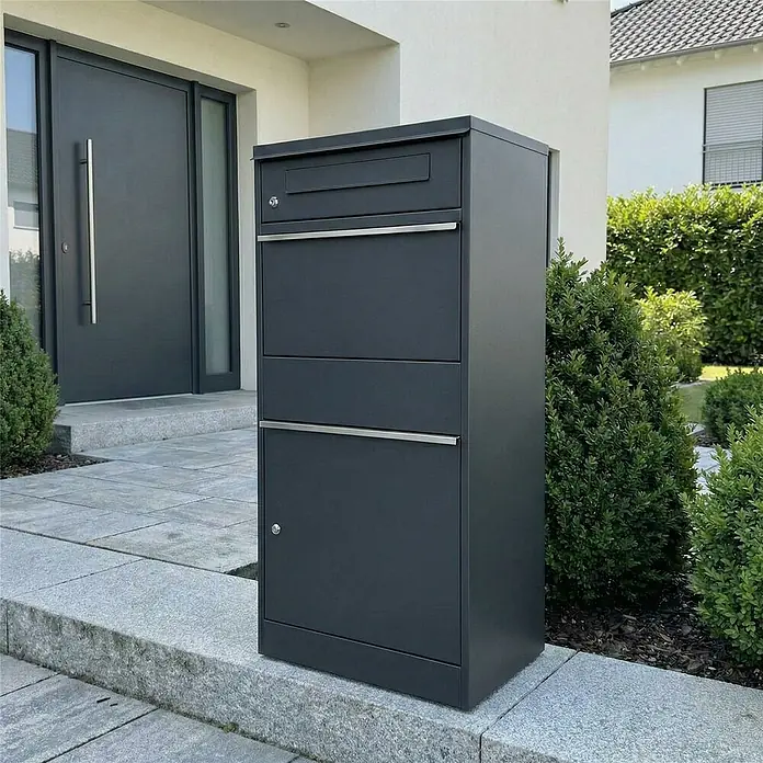Metzler Paketbox Bispo - L x B x H: 37,3 x 50,2 x 112 cm, Anthrazit, Stahl, Paketfach - Anthrazitfarbener Metall-Briefkasten/Paketbox auf gepflastertem Weg vor einem modernen Hauseingang.