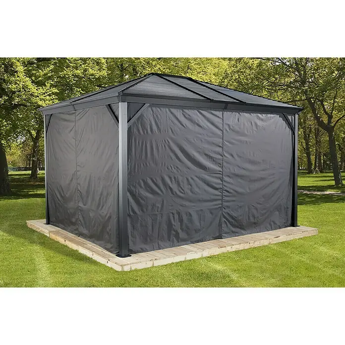 Sojag Pavillon-Seitenwand Ventura - Für Sojag Pavillon Ventura 10x14 - Überdachter Pavillon mit schwarzen Vorhängen auf einem Holzsockel, umgeben von üppigem Grün.