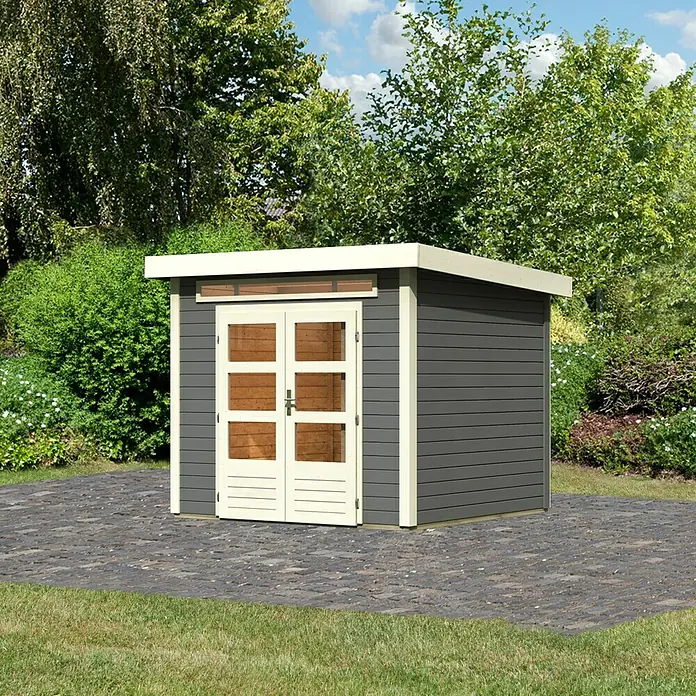 Karibu Gartenhaus Kandern 3 - Außenmaß inkl. Dachüberstand (B x T): 276 x 273 cm, Holz, Terragrau - Eine moderne, grau gestrichene Gartensauna mit weißen Akzenten und Doppeltür mit Glaseinsätzen. Sie steht auf einem gepflasterten Bereich im Grünen.